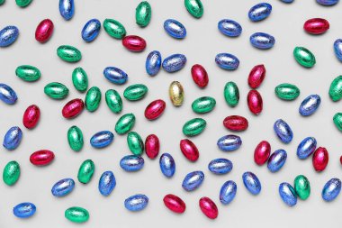 Açık arkaplanda renkli folyoyla çikolatalı Paskalya yumurtaları.