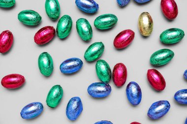 Açık arkaplanda renkli folyoyla çikolatalı Paskalya yumurtaları.