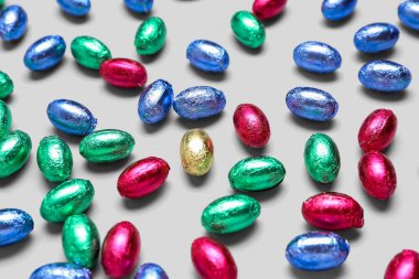 Hafif arka planda renkli folyoyla çikolatalı Paskalya yumurtaları, yakın plan.