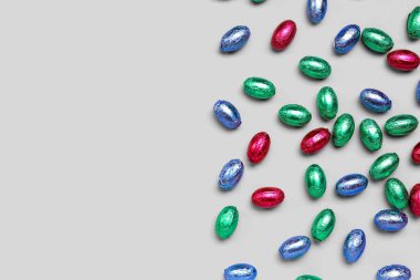 Açık arkaplanda renkli folyoyla çikolatalı Paskalya yumurtaları.