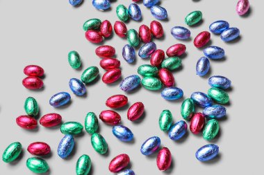 Chocolate Easter eggs in foil on light background
