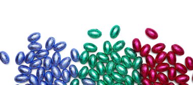 Beyaz arka planda renkli folyoya sarılı çikolatalı Paskalya yumurtaları.