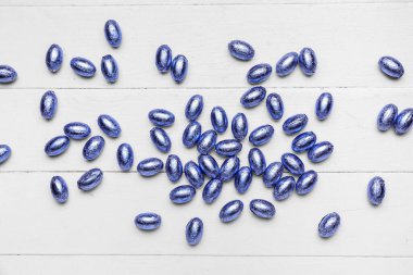 Hafif ahşap arka planda renkli folyoyla çikolatalı Paskalya yumurtaları.