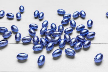 Hafif ahşap arka planda renkli folyoyla çikolatalı Paskalya yumurtaları.