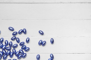 Hafif ahşap arka planda renkli folyoyla çikolatalı Paskalya yumurtaları.