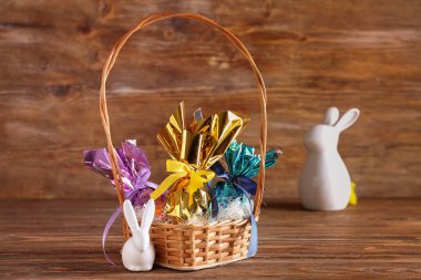 Çikolatalı sepet Paskalya yumurtası ve seramik tavşanlar ahşap masada.