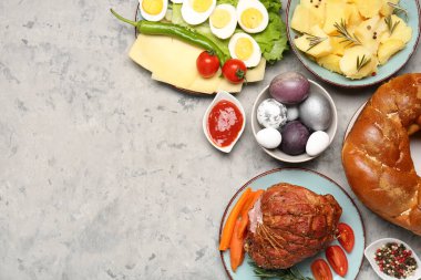 Tasty dishes and painted eggs for Easter dinner on grunge background