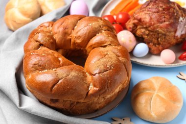 Paskalya çelengi ekmeği ve tabaklar renkli masaya, yakın plan.