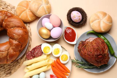 Tasty dishes and painted eggs for Easter dinner on color background
