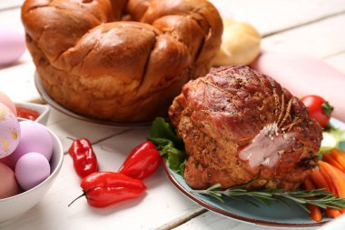 Paskalya yemeği için nefis jambon ve çelenkli ekmek tabağı, ahşap masa, yakın plan.
