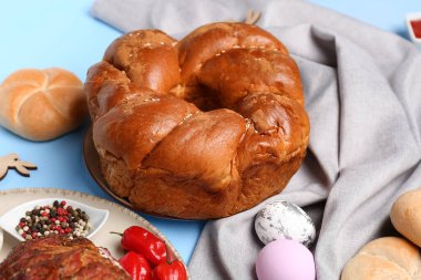 Paskalya çelengi ekmeği ve tabaklar renkli masaya, yakın plan.