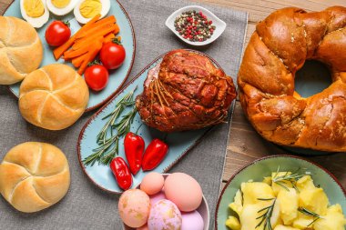 Tasty dishes and painted eggs for Easter dinner on wooden table