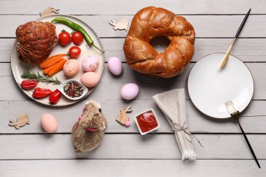 Easter table setting, painted eggs and decor on light wooden background