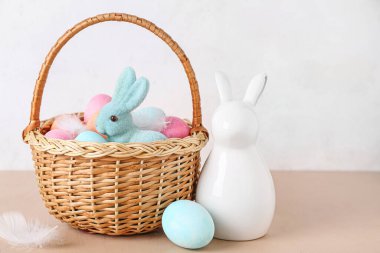 Paskalya yumurtası ve tavşanlı sepet bej masa üzerinde beyaz arka planda