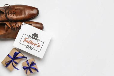 Mutlu Babalar Günü yazılı kart, şık erkek ayakkabıları ve beyaz arka planda hediyeler.