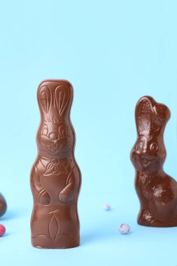 Mavi arka planda yumurtaları olan Paskalya tavşanları.