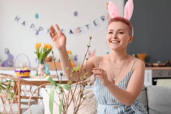 Evde Paskalya yumurtasıyla ağaç dallarını süsleyen genç bir kadın.