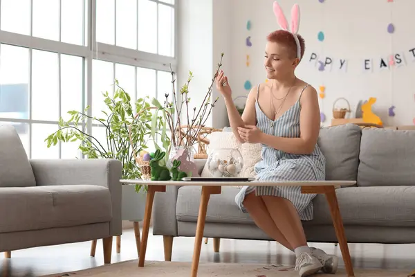 Evde Paskalya yumurtasıyla ağaç dallarını süsleyen genç bir kadın.