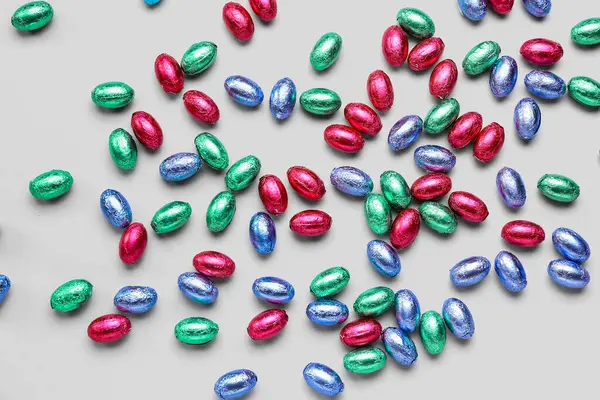 Chocolate Easter eggs in foil on light background