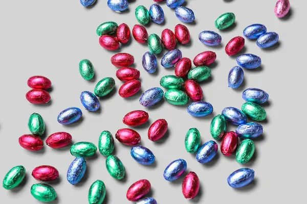 Chocolate Easter eggs in foil on light background