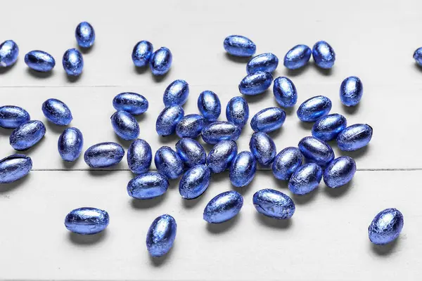 Hafif ahşap arka planda renkli folyoyla çikolatalı Paskalya yumurtaları.