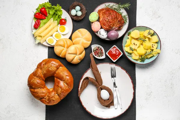 Easter table setting with tasty dishes on light background