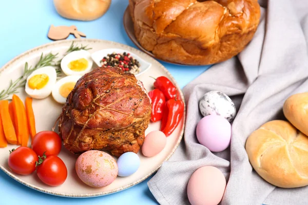 Tasty dishes for Easter dinner and beautiful painted eggs on color background, closeup