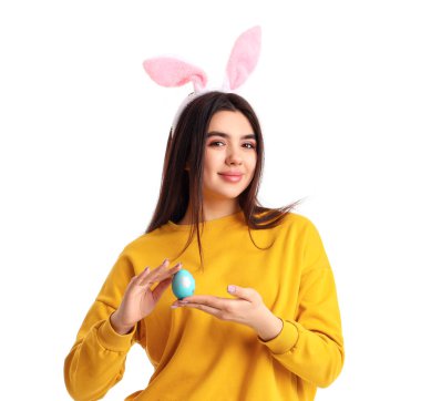 Beyaz arka planda Paskalya yumurtası olan tavşan kulaklı genç bir kadın.