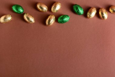 Kahverengi arka planda folyoda çikolatalı Paskalya yumurtaları