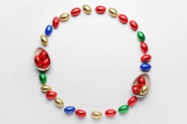 Beyaz arka planda folyoda çikolatalı Paskalya yumurtalarından yapılmış çerçeve.