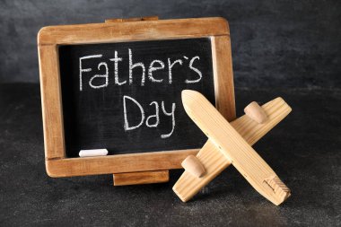 Üzerinde Babalar Günü yazılı yazı tahtası ve arka planda ahşap uçak