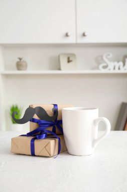 Odada hediyeler ve kağıt bıyıklı bir fincan. Babalar günü kutlaması.