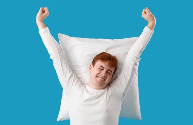 Mavi arka planda yumuşak yastıklı genç adam