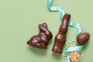 Çikolatalı Paskalya yumurtaları ve yeşil arka planda tavşanlar.