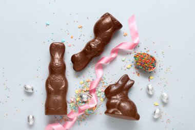 Çikolatalı Paskalya yumurtaları ve mavi arka planda tavşanlar.