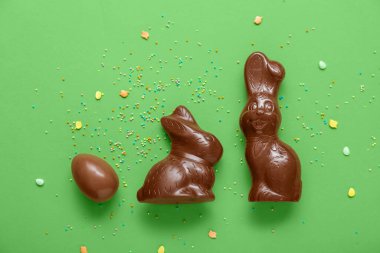 Çikolatalı Paskalya yumurtası ve yeşil arka planda tavşanlar.