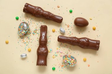 Çikolatalı Paskalya yumurtaları ve sarı arka planda tavşanlar.