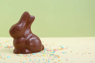 Çikolatalı Paskalya tavşanı ve renkli arka plana serpiştirilmiş çikolata.