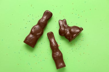 Çikolatalı Paskalya tavşanları ve yeşil arka planda serpiştirilmiş çikolata.