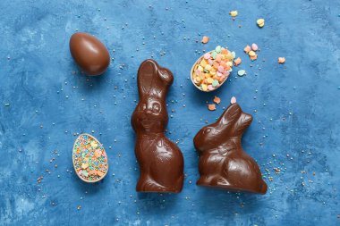 Çikolatalı Paskalya yumurtaları ve mavi arka planda tavşanlar.