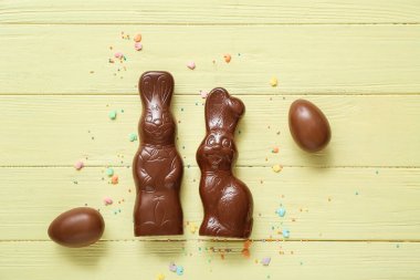 Çikolatalı Paskalya yumurtaları ve sarı ahşap arka planda tavşanlar.
