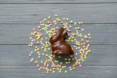 Çikolatalı Paskalya tavşanı ve gri ahşap arka plana serpiştirilmiş.