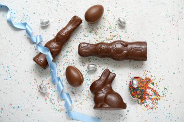 Çikolatalı Paskalya yumurtaları ve gri arka planda tavşanlar.