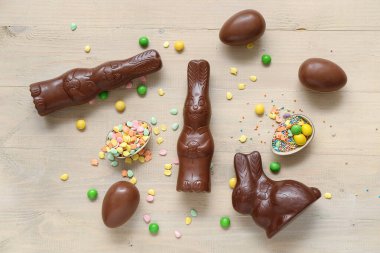 Çikolatalı Paskalya yumurtaları ve bej ahşap arka planda tavşanlar.