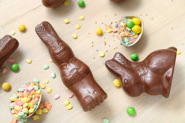 Çikolatalı Paskalya yumurtaları ve bej ahşap arka planda tavşanlar.