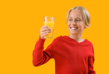 Arka planda bir bardak portakal suyu olan küçük çocuk.