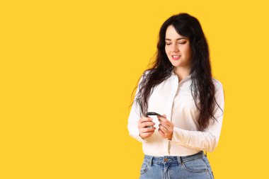 Sarı arka planda para sayan genç bir kadın.