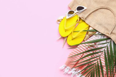 Plaj aksesuarları ve pembe arka planda palmiye yaprağı olan kompozisyon