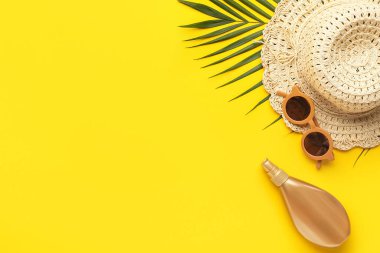 Plaj aksesuarları ve sarı arka planda palmiye yaprağı olan kompozisyon