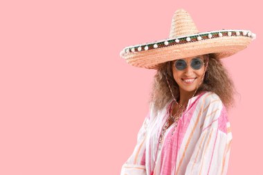 Pembe arka planda şapkalı olgun bir kadın. Meksika Ölüler Günü (El Dia de Muertos) kutlamaları